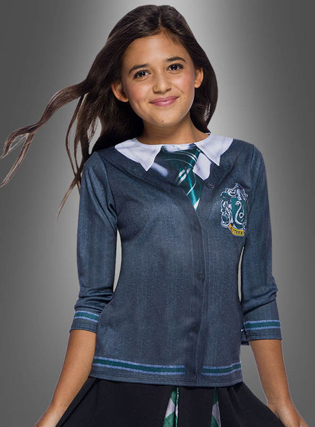 Ein Mädchen mit langen braunen Haaren trägt das „Slytherin-Shirt Harry Potter für Kinder“, einen Pullover im Slytherin-Design mit aufgedruckter Krawatte und weißem Kragen, und steht vor einem grauen Hintergrund.