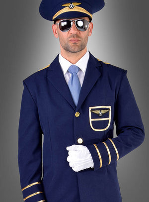 Ein Mann im „Pilot-Kostüm für Herren“ – aus marineblauem Stoff mit goldenen Akzenten, mit Sonnenbrille, Hut und weißen Handschuhen – steht vor einem grauen Hintergrund mit Farbverlauf.