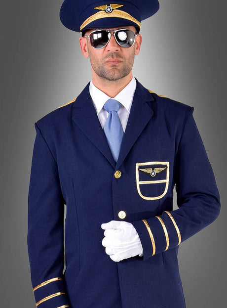Ein Mann im „Pilot-Kostüm für Herren“ – aus marineblauem Stoff mit goldenen Akzenten, mit Sonnenbrille, Hut und weißen Handschuhen – steht vor einem grauen Hintergrund mit Farbverlauf.