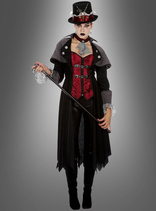 Eine Person in einem roten Korsett, einem schwarzen Mantel, einer schwarzen Hose und einem Zylinder hält einen Spazierstock in der Hand und steht vor einem grauen Hintergrund, um das auffällige „Vampir Gothic Mantel Lady Demona“-Kostüm zu präsentieren, das einen eleganten und dramatischen Eindruck hinterlässt.