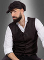 Ein bärtiger Mann, der das „20er-Jahre-Set“ aus Weste und Mütze trägt – das an ein klassisches „Peaky Blinders“-Kostüm erinnert –, dazu ein weißes Hemd und eine dunkle Weste, sitzt vor einem grauen Hintergrund mit Farbverlauf und blickt mit ernstem Gesichtsausdruck in die Kamera.
