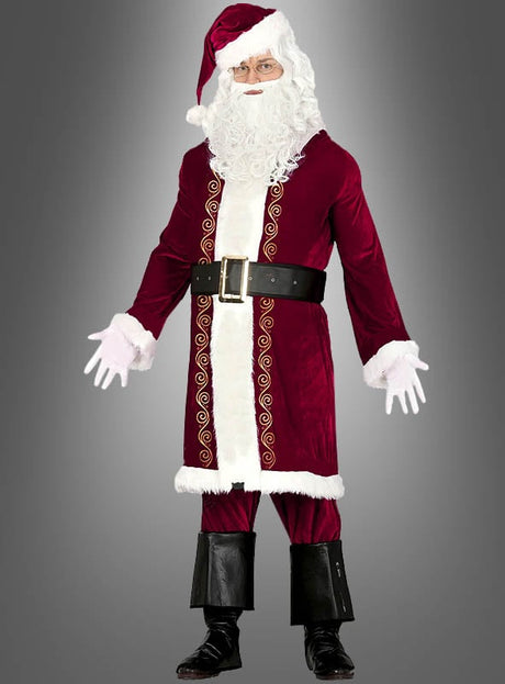 Eine Person in einem 5-teiligen Nikolauskostüm, bestehend aus einem klassischen roten Mantel, einem weißen Bart, einer Brille, einem schwarzen Gürtel, schwarzen Stiefeln mit markanten Stiefelüberzügen und weißen Handschuhen, die vor einem grauen Hintergrund steht.