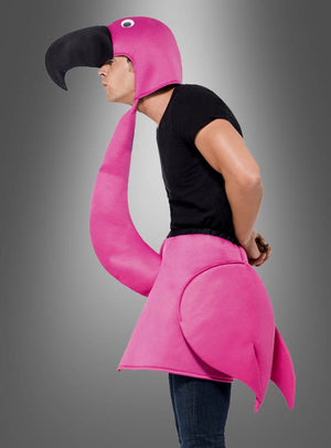 Eine Person in schwarzem T-Shirt und Jeans präsentiert das „Flamingo Vogel“-Unisex-Kostüm mit einem auffälligen Kopfschmuck, der über den Kopf hinausragt, und bunten Flügeln, die um die Taille drapiert sind – eine ideale Wahl für Karnevalsfeiern –, vor einem grauen Hintergrund mit Farbverlauf.