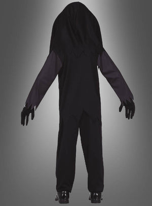 Eine Person steht mit dem Rücken zur Kamera und trägt das „Skelett-Kostüm mit Totenkopf für Kinder“ – ein schwarzes Kostüm mit Kapuze, dessen Ärmel und Saum gezackt sind – sowie schwarze Handschuhe und Schuhe vor einem grauen Hintergrund mit Farbverlauf.