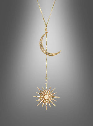 Goldfarbene Halskette „Sonne und Mond“: Diese elegante Halskette besticht durch einen funkelnden Halbmond-Anhänger mit eingefassten Steinen, der über eine feine Kette mit einem Sunburst-Anhänger verbunden ist – stilvoll arrangiert vor einem sanften, grauen Farbverlauf.