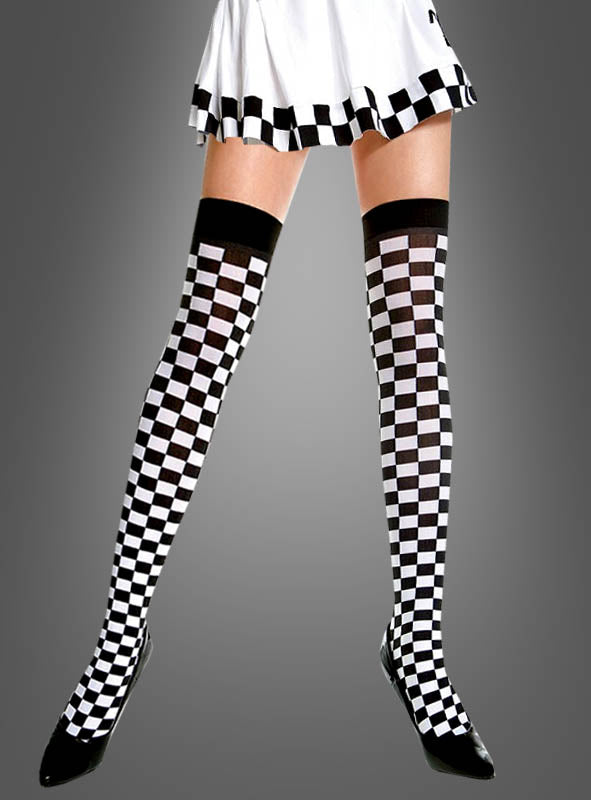 Eine Person, die einen weißen Rock mit schwarz-weißem Schachbrettmuster und dazu passende „Schachbrett“-Overknees ohne Riemchen trug, posierte vor einem grauen Hintergrund für einen klassischen Ska-Look.