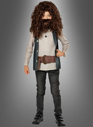Ein Kind trägt das Deluxe-Hagrid-Kinderkostüm aus „Harry Potter“, bestehend aus einer großen braunen Perücke und einem Bart, einem beigen Hemd, einer dunklen Weste, einem breiten Gürtel, einer dunklen Hose und schwarzen Schuhen – damit ist es die ideale Wahl für jeden jungen „Harry Potter“-Fan, der einen authentischen Look sucht –, während es vor einem grauen Hintergrund mit Farbverlauf steht.