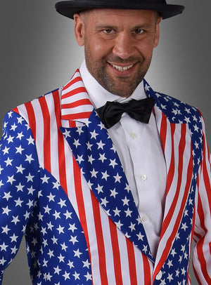 Ein Mann, der den „Stars and Stripes USA Frack“ trägt, der durch sein lebhaftes Muster in den Farben der amerikanischen Flagge besticht, kombiniert diesen mit einem weißen Hemd, einer schwarzen Fliege und einem schwarzen Hut und lächelt selbstbewusst in seinem auffälligen Kostüm.