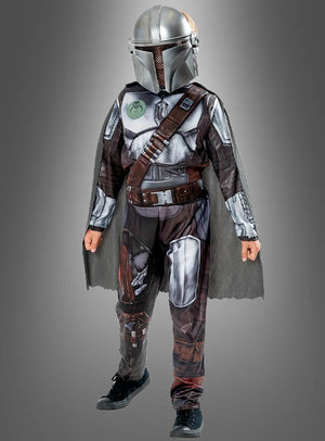 Ein Kind im Mandalorianer-Kinderkostüm aus „Star Wars“ – bestehend aus Helm, Umhang und bedruckter Rüstung – steht vor einem schlichten grauen Hintergrund – ideal für jeden jungen „Star Wars“-Kostümfan.