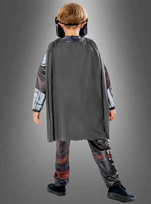 Ein Kind, das das Mandalorianer-Kinderkostüm aus „Star Wars“ trägt – bestehend aus einem grauen Umhang, schwarzen Schuhen und einer schwarzen Maske –, steht mit dem Rücken zur Kamera vor einem grauen Hintergrund.