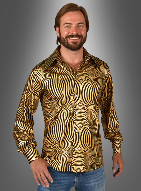 Ein lächelnder Mann mit Bart trägt ein glänzendes, gold-schwarz gemustertes „Hologramm Party Hemd“ sowie eine blaue Jeans und steht vor einem grau verlaufenden Hintergrund.