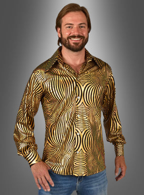 Ein lächelnder Mann mit Bart trägt ein glänzendes, gold-schwarz gemustertes „Hologramm Party Hemd“ sowie eine blaue Jeans und steht vor einem grau verlaufenden Hintergrund.