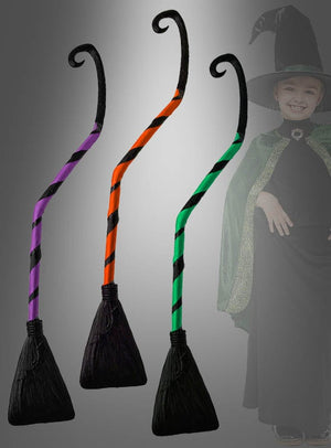 Zu sehen sind drei Krummer Hexenbesen (90 cm) für Kinder in gestreiften Designs in Lila, Orange und Grün mit schwarzen Borsten; im Hintergrund ist ein Kind in einem Hexenkostüm zu sehen, wodurch diese Besen das ideale Hexenkostüm-Zubehör sind.