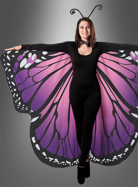 Eine Person steht mit ausgestreckten Armen vor einem grauen Hintergrund und präsentiert die „Schmetterlingsflügel 2-seitig bedruckt Erwachsene“ – ein Set aus großen, violetten und schwarzen Schmetterlingsflügeln und Fühlern, die über einem schwarzen Outfit getragen werden – perfekt für einen auffälligen Kostüm-Look.