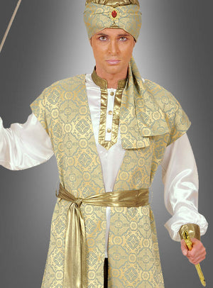 Eine Person, die das „Prinz Karan“-Bollywood-Kostüm für Herren trägt – bestehend aus einer Robe mit Gold- und Elfenbeinmuster, einem passenden Kopfschmuck, der mit einem roten Edelstein verziert ist, ein weißes Hemd sowie ein Schwert in der Hand – steht vor einem schlichten grauen Hintergrund, wodurch sich dieses auffällige indische Prinzenkostüm ideal für jede Karnevals- oder Bollywood-Veranstaltung eignet.