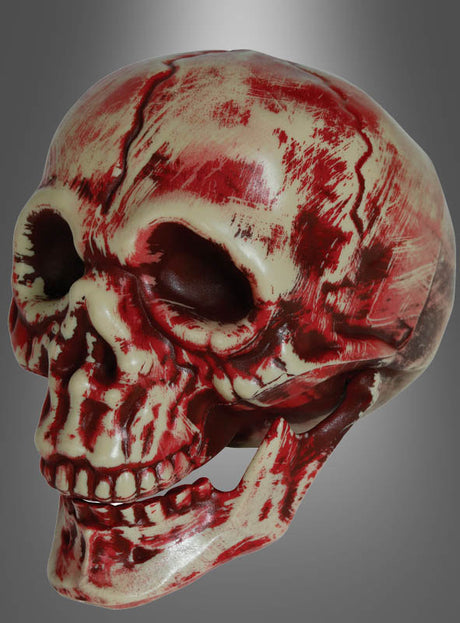 Der „Blutige Totenschädel“ – ein mit blutroten Streifen bemalter Plastikschädel – ist ein auffälliges Halloween-Dekorationselement, besonders wenn er vor einem grauen Hintergrund mit Farbverlauf präsentiert wird.