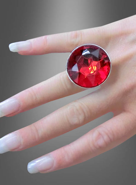 Eine Hand mit langen, gepflegten Nägeln trägt den Ring mit rotem Edelstein (verstellbar) am Mittelfinger vor einem grau abgestuften Hintergrund – ein auffälliges Stück Halloween-Schmuck.