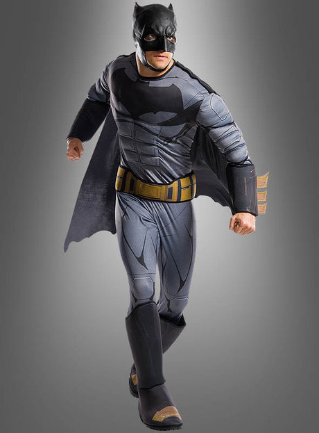 Ein Mann steht allein vor einem grauen Hintergrund und trägt das Batman-Kostüm „Original Justice League“ – einen Ganzkörperanzug mit aufgedrucktem Muskelmuster, schwarzer Kapuze, Umhang, gelbem Werkzeuggürtel und schwarzen Handschuhen –, was es zu einem originalen Lizenzkostüm macht, das sich perfekt für jede Justice-League-Kostümsammlung eignet.