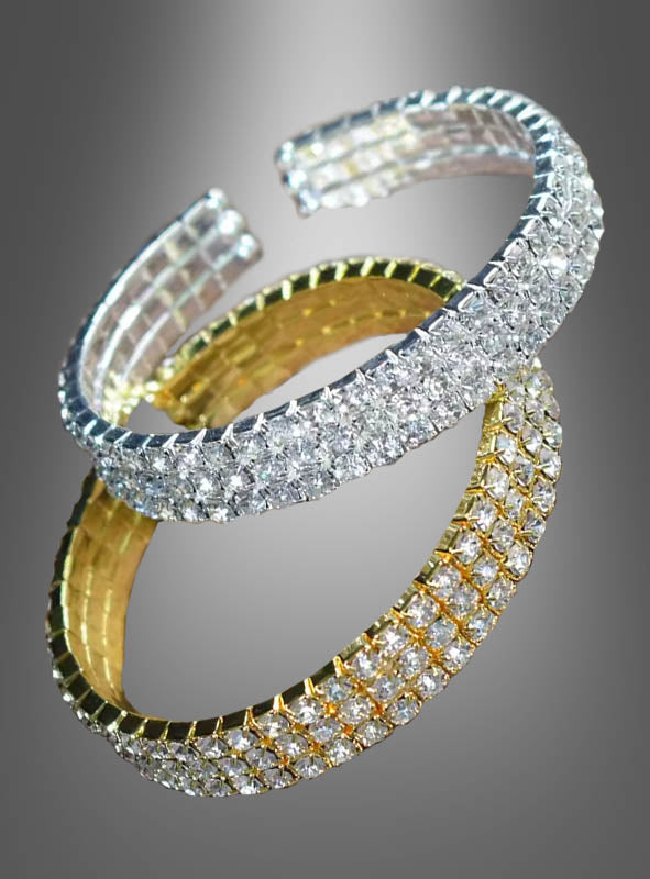 Der Armreif mit Strasssteinen in Gold oder Silber – erhältlich sowohl in strahlendem Gold als auch in elegantem Silber – schimmert mit Reihen aus klaren Edelsteinen und wird vor einem grauen Hintergrund mit Farbverlauf präsentiert, wodurch die glamouröse Eleganz eines Kostüms aus den 20er Jahren eingefangen wird.