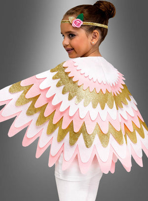 Ein junges Mädchen trägt das schimmernde „Glitzer Cape Flügel für Kinder“ mit goldenen, rosa und weißen Federn, dazu ein goldenes Stirnband, das mit einer rosa Blume verziert ist, und steht vor einem grauen Hintergrund.
