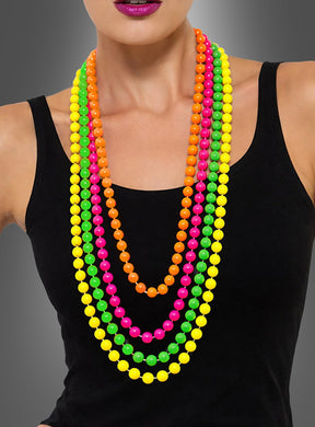 Eine Person, die das „Neon Perlenketten 4er Set bunt“ trägt – bunte, übereinander getragene Halsketten in Gelb, Grün, Rosa und Orange –, kombiniert mit einem schwarzen, ärmellosen Oberteil und lila Lippenstift vor einem grauen Farbverlaufshintergrund; ideal für jedes 80er-Jahre-Kostüm oder als lustiges Accessoire für eine Neonparty.