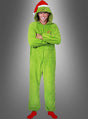 Eine Person, die den „Der Grinch“-Kigurumi-Overall trägt – ein grünes Modell mit Kapuze und aufgesetzter Weihnachtsmannmütze –, steht mit verschränkten Armen vor einem grauen Hintergrund und lächelt.