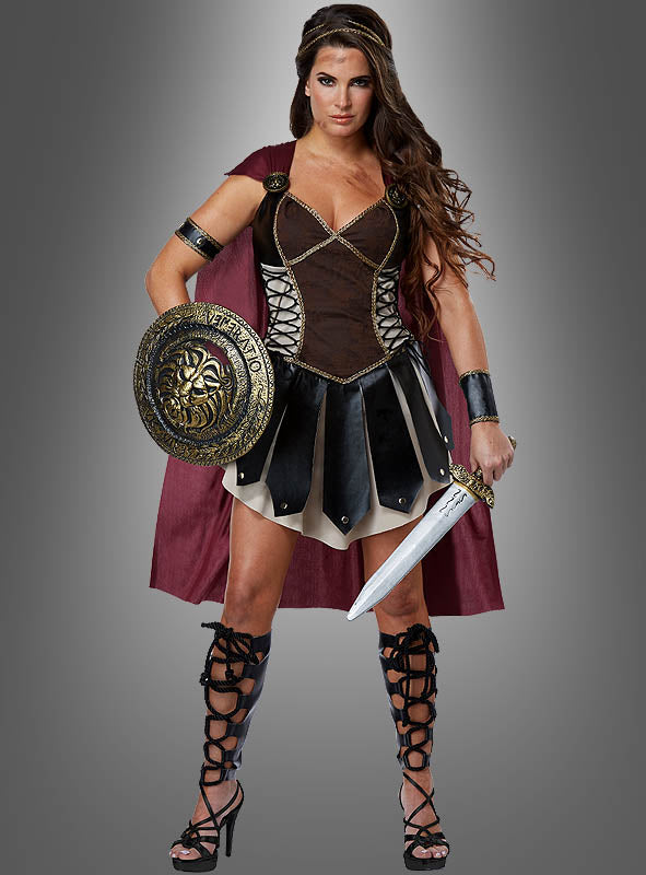 Vor einem grauen Hintergrund steht eine Frau, die das „Sexy Gladiatorin“-Kostüm „Kriegerin“ trägt – mit einem roten Umhang, schwarzer Rüstung, Sandalen und Armbändern – und einen runden Schild sowie ein Schwert in den Händen hält.