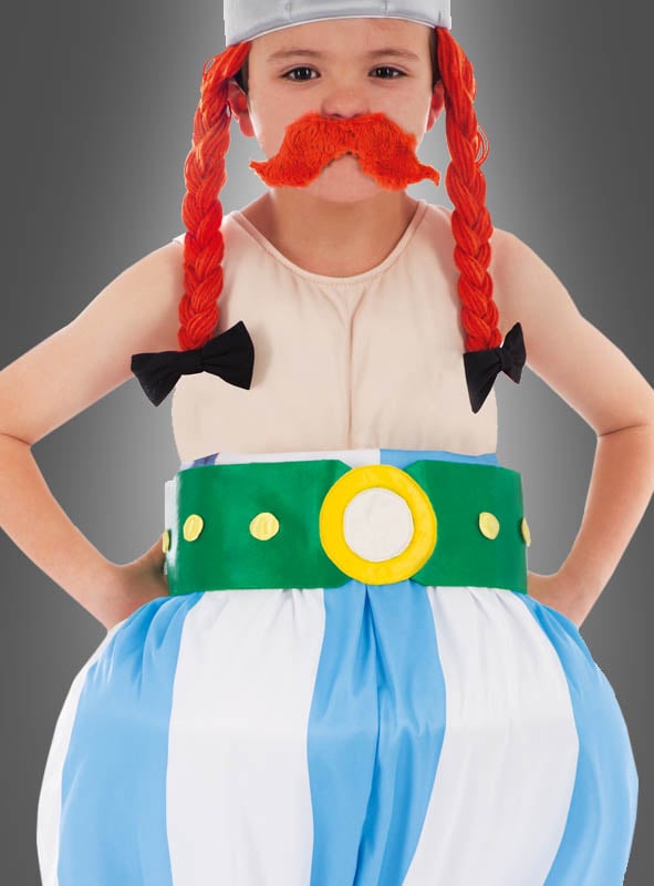 Ein Kind im „Deluxe Original Obelix“-Kinderkostüm aus der Asterix-Reihe, bestehend aus einer roten Zopfperücke, einem orangefarbenen Kunstschnurrbart, einer gestreiften Hose und einem grünen Gürtel vor grauem Hintergrund – ideal als Asterix-Kostüm oder Fasching-Kinderkostüm.