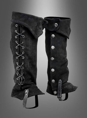 Die aus schwarzem Wildleder gefertigten Gamaschen-Stiefelüberzieher „Piraten & Steampunk“ sind auf der einen Seite mit Schnürsenkeln versehen und lassen sich auf der anderen Seite mit Knöpfen und einer Schnalle schließen. Sie werden vor einem grau verlaufenden Hintergrund präsentiert – und sind damit das ideale Kostümzubehör für einen eleganten letzten Schliff.