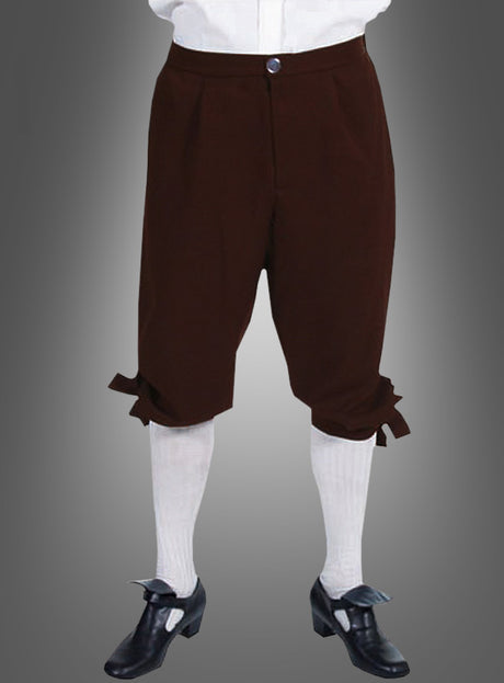 Eine Person, die die „Braune Kniebundhose Steampunk“ trägt, kombiniert mit weißen Strümpfen, einem weißen Hemd und schwarzen Schuhen im Kolonialstil mit Schnallen, steht vor einem grauen Hintergrund – ein Ensemble, das an historische Kostüme erinnert.