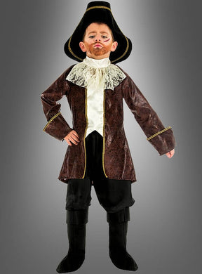 Ein Kind trägt das „Piratenkapitän“-Kinderkostüm, bestehend aus einem großen schwarzen Hut, einem braunen Mantel, einem Spitzenkragen, einer schwarzen Hose und schwarzen Stiefeln, und posiert mit einer Hand in die Hüfte gestützt vor einem grauen Hintergrund.