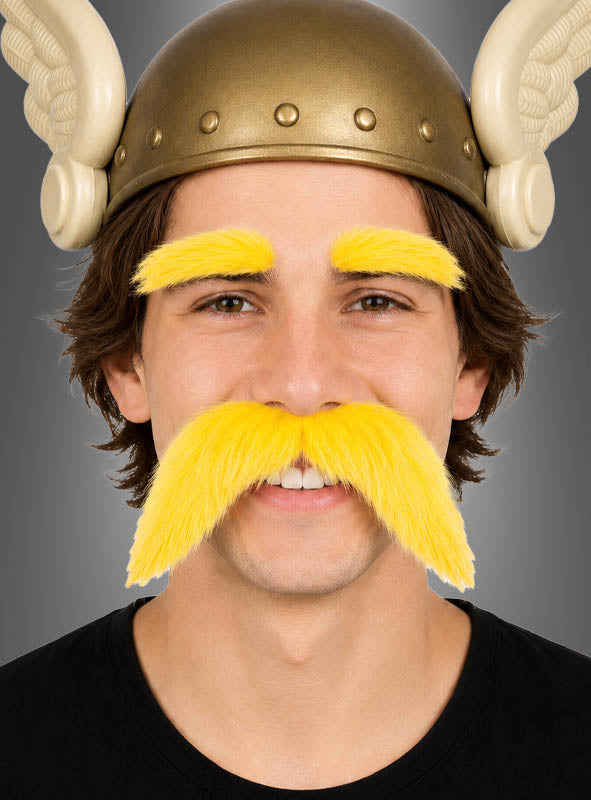 Eine Person, die einen Wikingerhelm mit Flügeln trägt und deren leuchtend gelbe Augenbrauen sowie der dazu passende Schnurrbart aus dem „Schnurrbart & Augenbrauen“-Set hervorstechen, lächelt in die Kamera.
