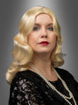Eine Frau mit welligem blondem Haar, das mit einer „Luxus 20er Premium Wasserwelle Perücke Elli“ frisiert ist, trägt ein schwarzes Top mit Pailletten und eine Perlenkette und posiert vor einem grauen Hintergrund mit Farbverlauf.