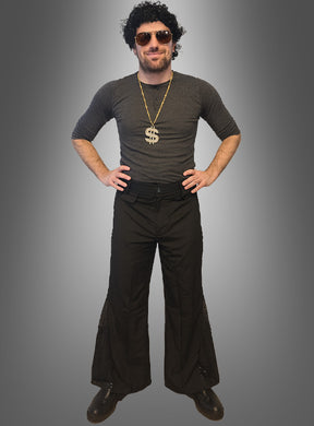 Ein Mann, der das „70er Disco-Fever-Set mit Schlaghose für Herren“ trägt – bestehend aus einer schwarzen Perücke, einer Sonnenbrille, einer Dollarzeichen-Halskette, einem dunklen Hemd und einer klassischen schwarzen Schlaghose – steht mit den Händen in den Hüften vor einem grauen Hintergrund. Damit ist dieses Set die perfekte Wahl für alle, die auf der Suche nach einem kultigen 70er-Jahre-Kostüm für Herren oder einem Disco-Outfit für Männer sind.