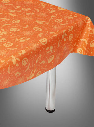Mehrweg-Tischdecke zu Halloween mit festlichen Motiven wie Kürbissen, Spinnen, Fledermäusen und Sternen – ideal als stimmungsvolle Halloween-Dekoration oder Kürbis-Tischdecke, stilvoll drapiert über einem rechteckigen Tisch mit sichtbaren Metallbeinen.