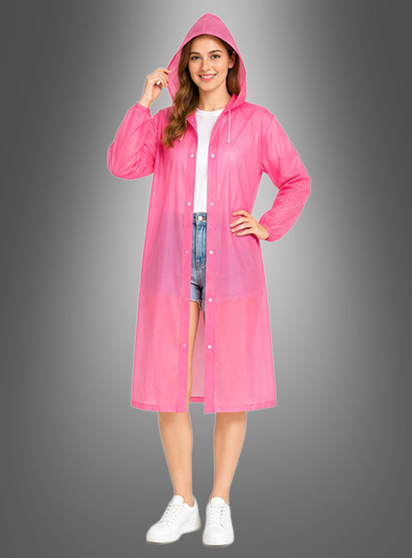 Eine Frau in einem rosa, langen, wetterfesten Regenmantel mit Kapuze, einem weißen Hemd, blauen Shorts und weißen Sneakers, die vor einem grauen Hintergrund mit Farbverlauf steht.