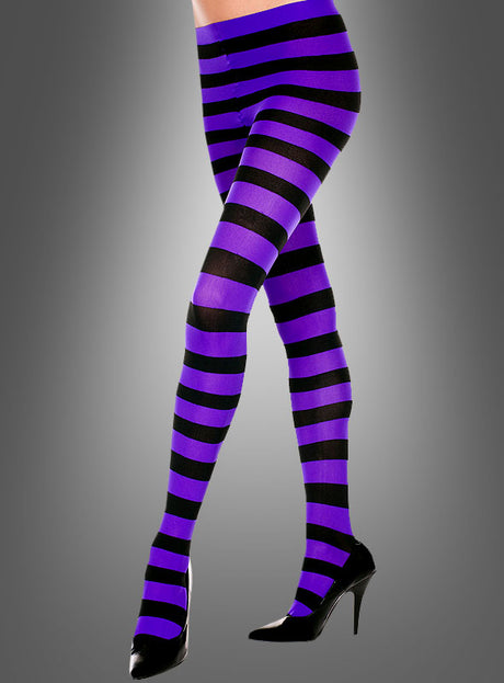 Ein Model trägt die „Ringelstrumpfhosen breit gestreift“ in violetten und schwarzen Querstreifen sowie schwarze Schuhe mit hohen Absätzen und steht vor einem grauen Hintergrund mit Farbverlauf.