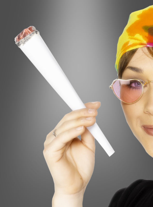 Eine Person mit einem Batik-Stirnband und einer rosa Sonnenbrille hält vor einem grauen Hintergrund einen überdimensionalen, brennenden „Riesen Joint Cannabis“ (22 cm) in der Hand – das perfekte Hippie-Kostüm-Accessoire für deine 70er-Jahre-Mottoparty.