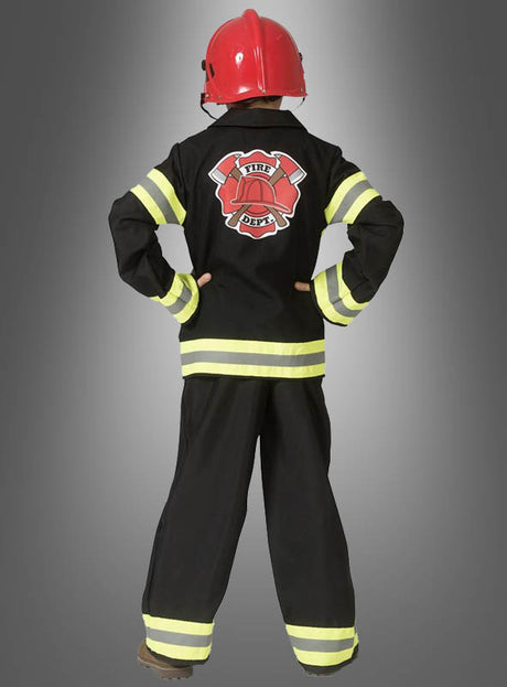 Ein Kind, das eine schwarze Feuerwehrmann-Uniform für Jungen mit reflektierenden Streifen und einen roten Feuerwehrhelm für Kinder trägt, steht mit dem Rücken zur Kamera und die Hände in die Hüften gestemmt.