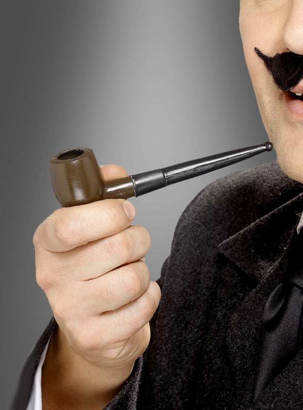 Eine Person, die einen schwarzen Anzug trägt und einen künstlichen schwarzen Schnurrbart trägt, hält eine braune Tabakpfeife für Sherlock Holmes aus Kunststoff vor den Mund, vor einem grauen Hintergrund mit Farbverlauf.