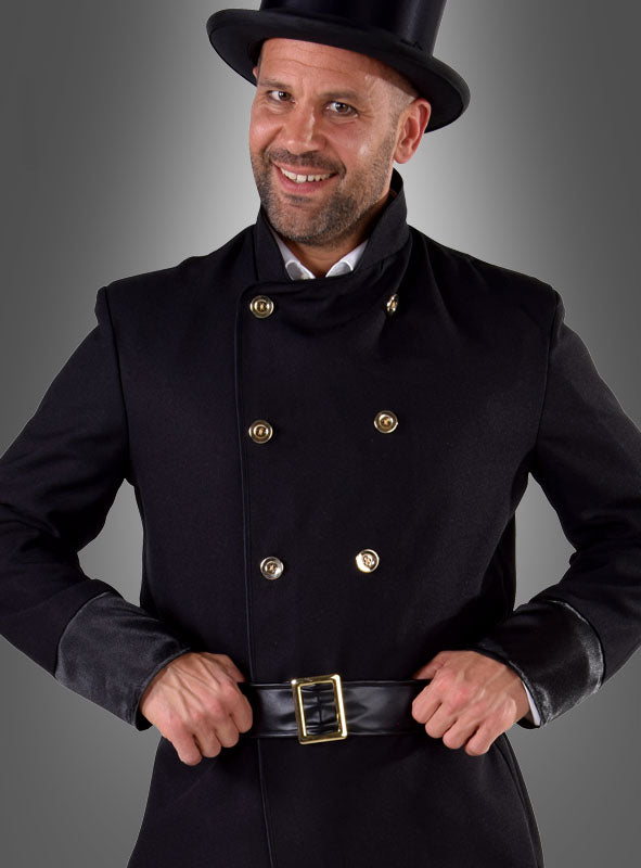 Ein Mann im Schornsteinfeger-Herrenkostüm – einem klassischen schwarzen Zweireiher mit goldenen Knöpfen, einem passenden schwarzen Gürtel und einem schwarzen Zylinder – lächelt in die Kamera. Dieses traditionelle Herrenkostüm ist als Glücksbringer bekannt, der jedem Glück bringt.