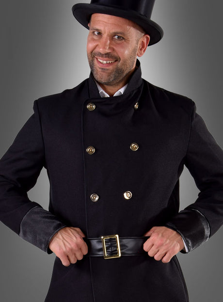 Ein Mann im Schornsteinfeger-Herrenkostüm – einem klassischen schwarzen Zweireiher mit goldenen Knöpfen, einem passenden schwarzen Gürtel und einem schwarzen Zylinder – lächelt in die Kamera. Dieses traditionelle Herrenkostüm ist als Glücksbringer bekannt, der jedem Glück bringt.
