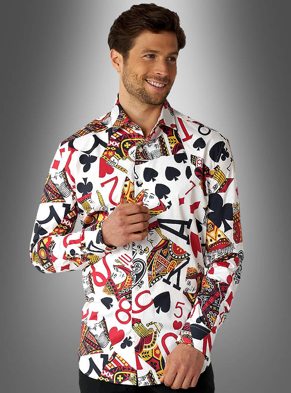 Ein Mann, der das „Spielkarten-Hemd“ von OppoSuits trägt – mit bunten Aufdrucken von Spielkartenfarben und Zahlen –, steht vor einem grauen Hintergrund mit Farbverlauf und lächelt.