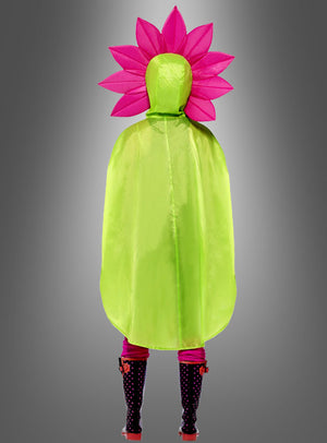 Eine Person, die das „Pink Blume Regencape“ in Grün trägt und deren Kopf mit einem Accessoire im „Pink Flower Power“-Stil geschmückt ist, steht mit dem Rücken zur Kamera vor einem grauen Hintergrund.