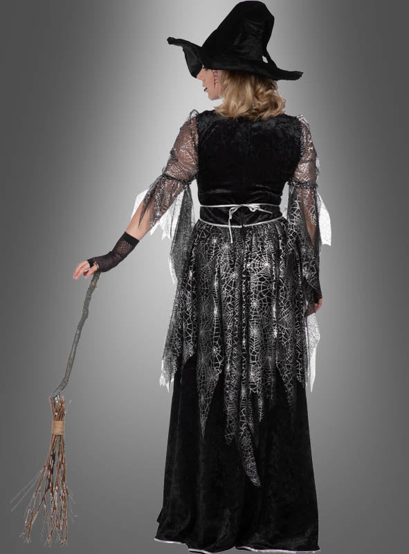 Eine Person, die ein „Hexenkleid Spinnennetz“ trägt, einen Hut auf dem Kopf hat, einen Besen in der Hand hält und mit dem Rücken zur Kamera vor einem grauen Hintergrund steht – ein bezauberndes Halloween-Kostüm, das perfekt zur Jahreszeit passt.