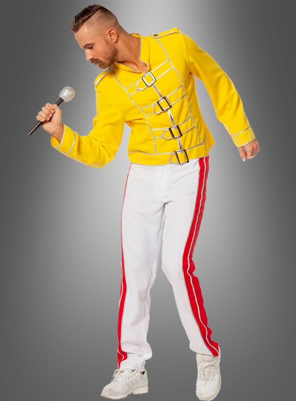Ein Mann im „Rockstar Champion Freddie“-Kostüm – einer gelben Jacke im Militärstil und einer weißen Hose mit roten Streifen – hält ein Mikrofon in der Hand und posiert vor einem grauen Hintergrund mit Farbverlauf, wobei er den legendären Queen-Look nachahmt und so das ultimative Party-Outfit der 80er Jahre kreiert.