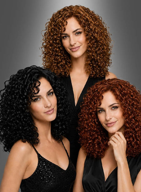 Drei Frauen mit schulterlangen Locken – im Stil von Donna Summer in auffälligen Schwarz-, Rotbraun- und Rottönen – posieren selbstbewusst in schwarzen Outfits vor einem grauen Hintergrund und verkörpern dabei jeweils die kühne Eleganz der Deluxe-Lockenperücke „Charly“.