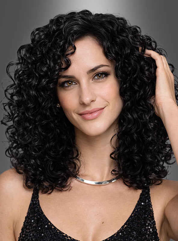 Eine Frau mit schulterlangem, dunklem Lockenhaar, das zu einer „Deluxe Lockenperücke Charly“ frisiert ist und an den Look von Donna Summer erinnert, sowie heller Haut lächelt leicht in die Kamera. Sie trägt ein schwarzes Pailletten-Top und eine silberne Halskette.