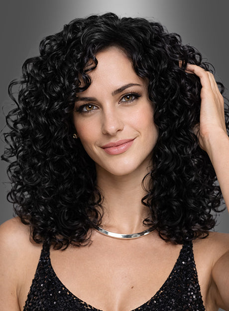 Eine Frau mit schulterlangem, dunklem Lockenhaar, das zu einer „Deluxe Lockenperücke Charly“ frisiert ist und an den Look von Donna Summer erinnert, sowie heller Haut lächelt leicht in die Kamera. Sie trägt ein schwarzes Pailletten-Top und eine silberne Halskette.
