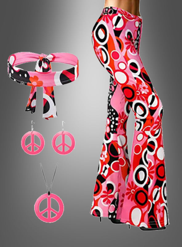Die Schlaghose mit dem Accessoire „Dream Circles“ in Rosa-Rot – mit rosa, schwarzen und weißen Retro-Mustern sowie einem passenden Stirnband, dazu rosa Peace-Zeichen-Ohrringe und eine Halskette – vor grauem Hintergrund ergibt das perfekte Hippie-Kostüm oder Outfit für eine Woodstock-Party.